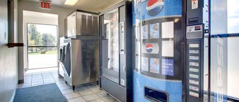Un'area con distributori automatici, inclusa una macchina di Pepsi, un frigorifero e un cartello di uscita.