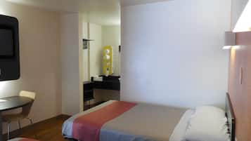 Quarto de hotel com duas camas, uma escrivaninha, uma cadeira, um espelho e uma televisão.