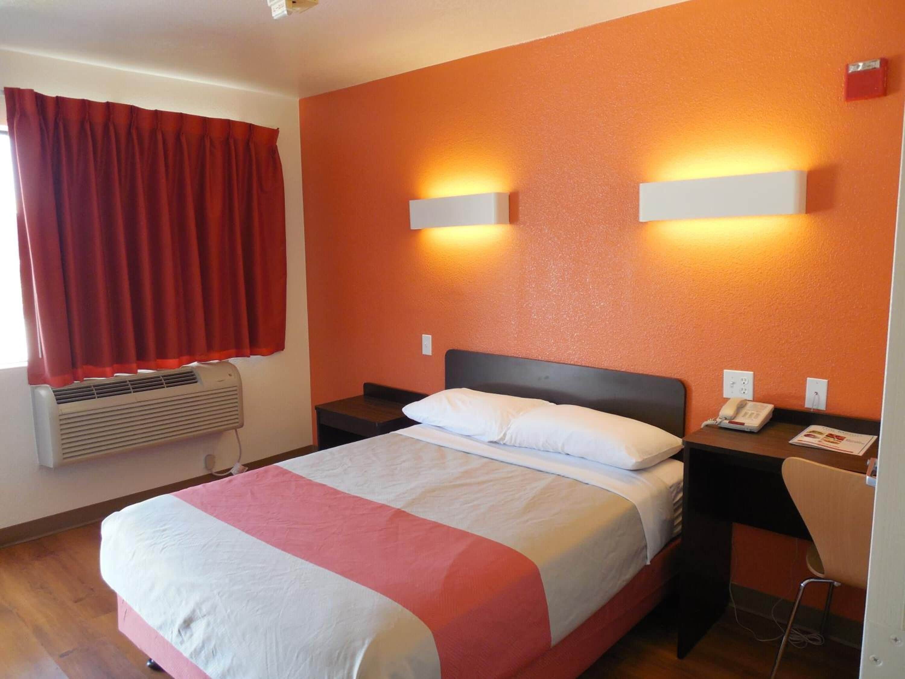 Ein Hotelzimmer mit einem Bett, zwei Nachttischen, einem Telefon und einem Wandheizkörper.