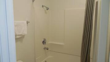 A shower area with a glass door, a towel rack, and a showerhead.
