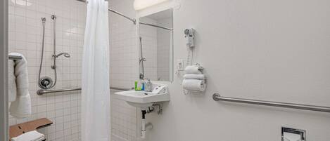 Un baño con ducha, lavamanos y secamanos.