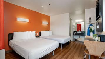 Habitación de hotel con dos camas, piso de madera, un escritorio con silla y televisión.