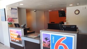 A hotel reception desk with a digital display, a clock, and a telephone. - Motel 6 Temecula, CA - Historic Old Town (Temecula)