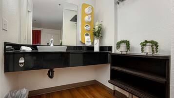 A modern bathroom with a black countertop, a white sink, a mirror, and a towel rack.