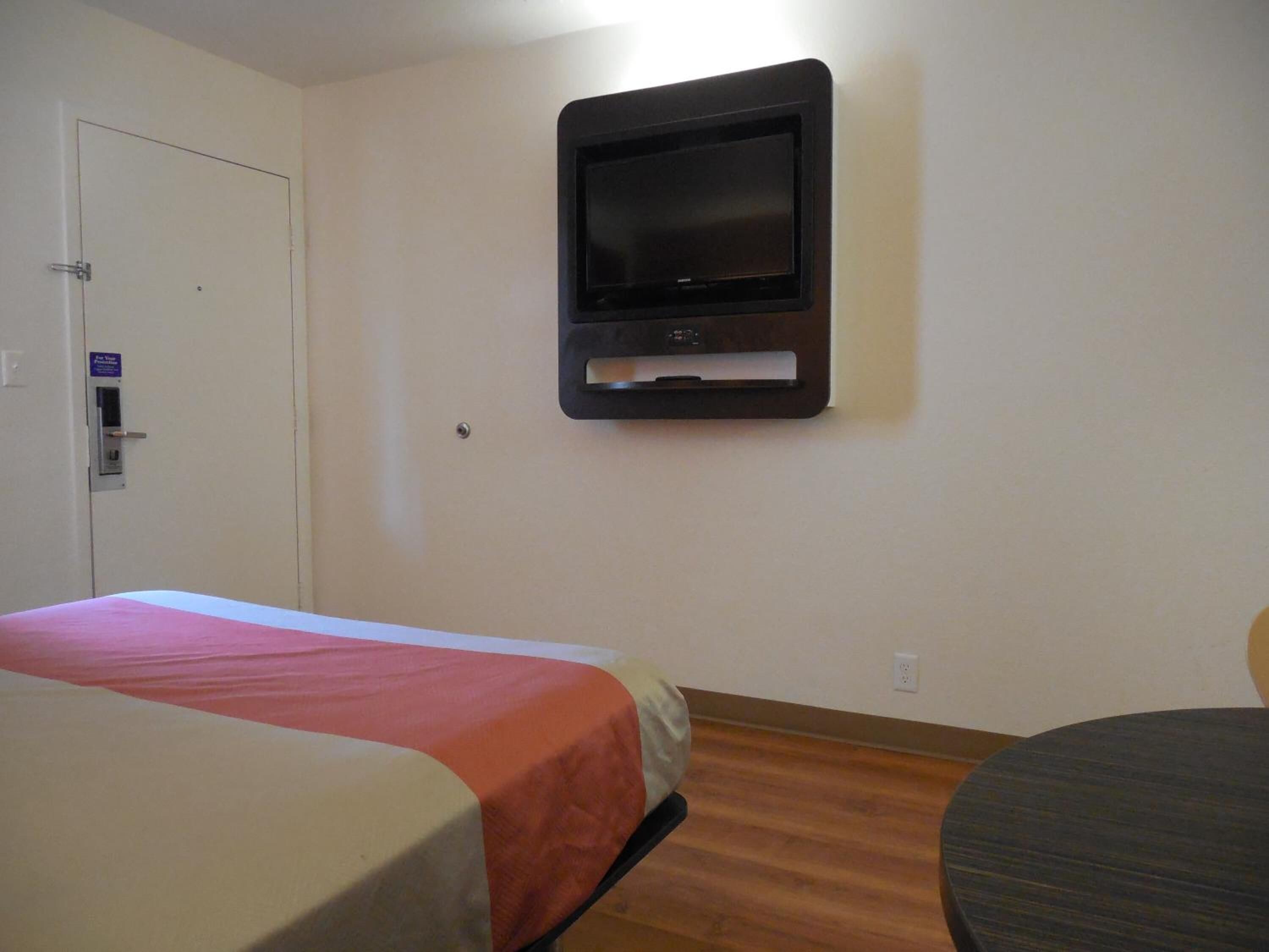 Une chambre d’hôtel équipée d’un lit, d’un téléviseur fixé au mur et d’une porte dotée d’un lecteur de carte magnétique.