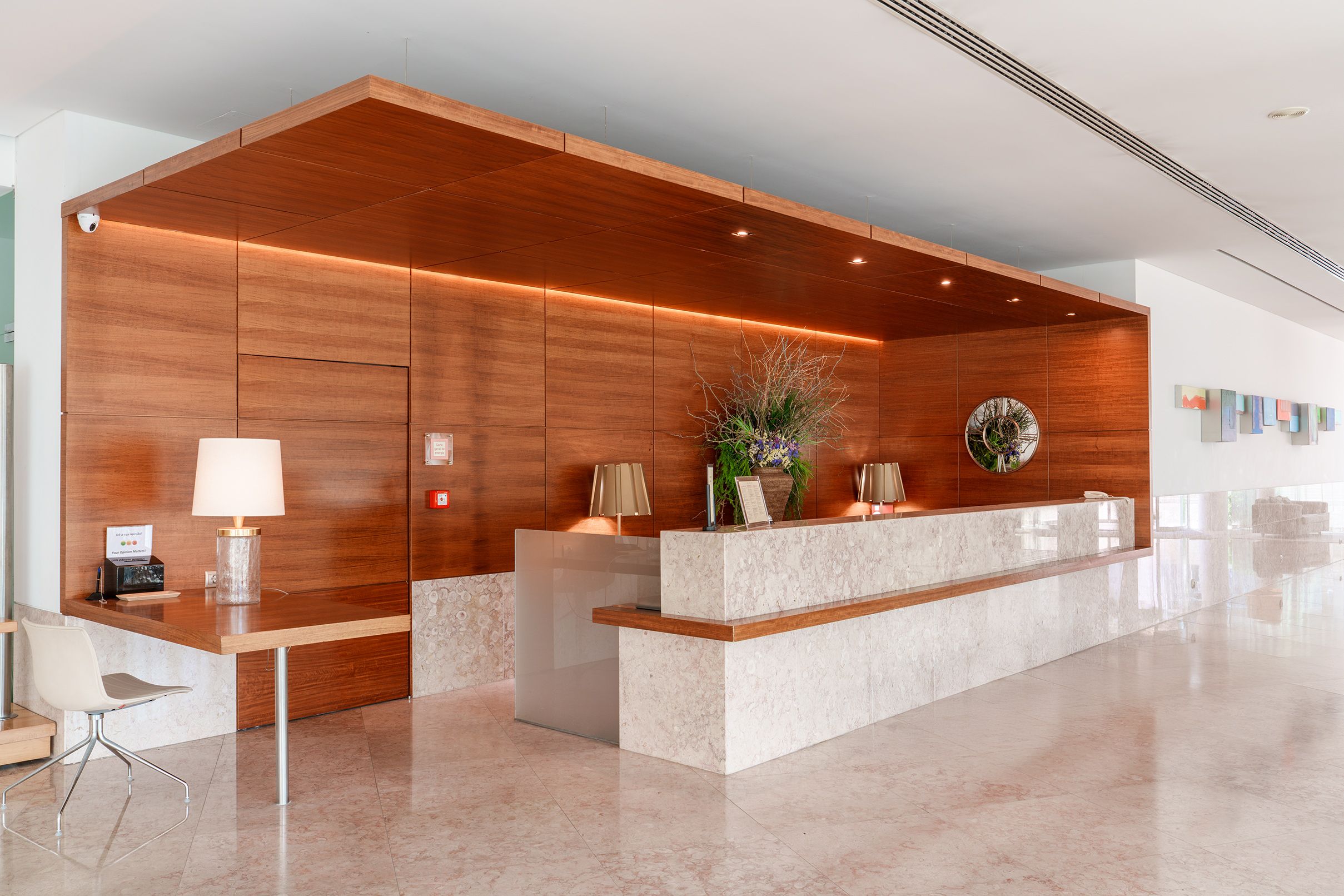 A reception desk with a wooden panel backdrop, a marble counter, and a potted plant.