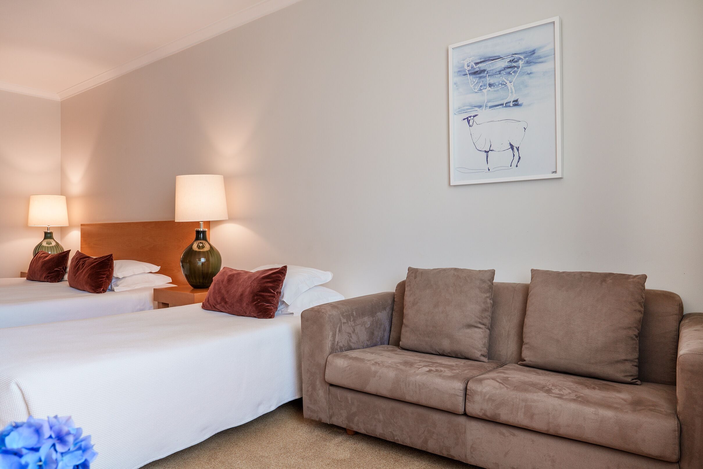 Habitación de hotel con dos camas, un sofá y un cuadro en la pared.