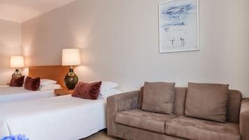Habitación de hotel con dos camas, un sofá y un cuadro en la pared.