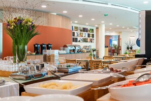 A modern cafe with a variety of seating options, a coffee bar, and a selection of beverages and food items. - Hotel Santa Maria (Ourem)