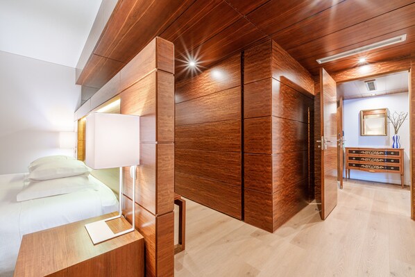 Habitación de hotel con cama, mesita de noche y armario de madera.