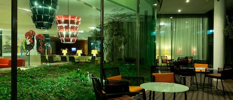 A modern indoor space with glass walls, a green garden area, and contemporary furniture.