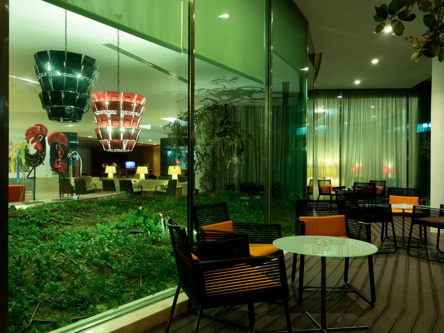 A modern indoor space with glass walls, a green garden area, and contemporary furniture.
