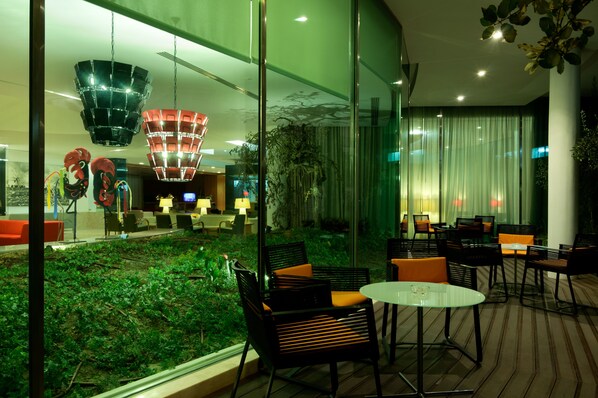 Un ambiente interno moderno con pareti in vetro, un'area giardino verde e arredi contemporanei.