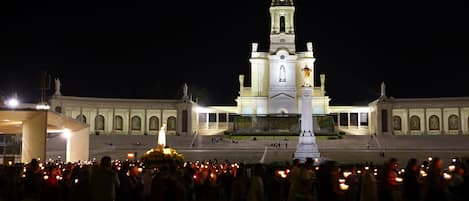Un edificio grande e iluminado con una torre destacada y una multitud reunida en su fachada.