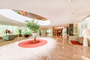 A modern hotel lobby with a central round table, seating area, and a large potted plant. - Hotel Santa Maria (Ourem)