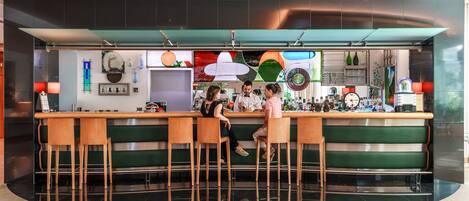 A bar area with stools, a counter, and various bottles and glasses.