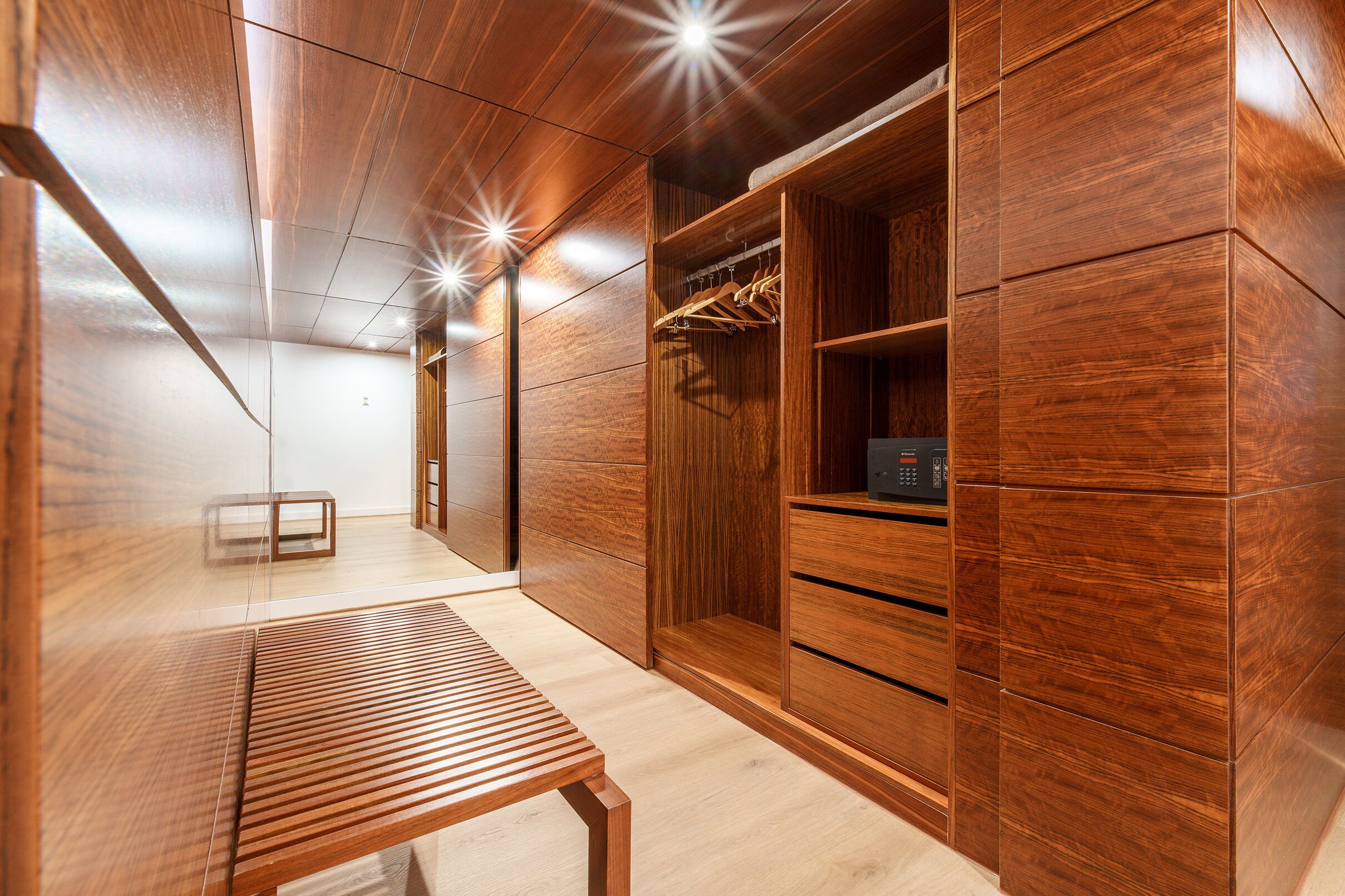 Un interior moderno de madera con un banco, un vestidor y un espejo.