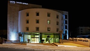 Un hotel de diseño moderno, con fachada curva, varias ventanas y un letrero llamativo.