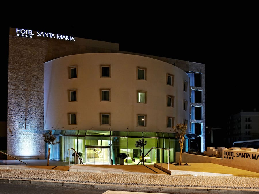 A hotel with a modern design, featuring a curved facade, multiple windows, and a prominent sign.