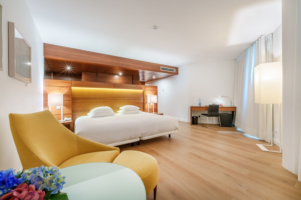 Una camera d'albergo con un letto, una scrivania, una sedia e un comodino.