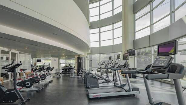 A modern gym with multiple treadmills, stationary bikes, and weight machines.