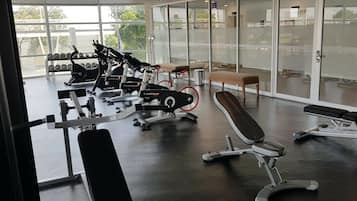 A gym with various exercise equipment, including treadmills and weight machines, and a bench.