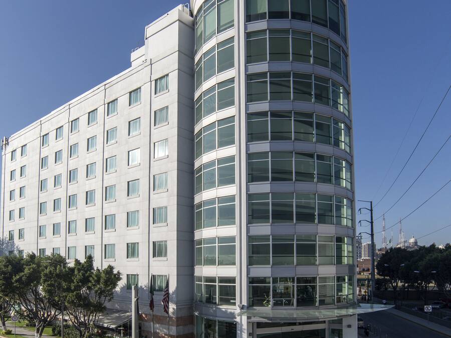Un moderno edificio de hotel con fachada de vidrio curvo, varios pisos y una entrada destacada.