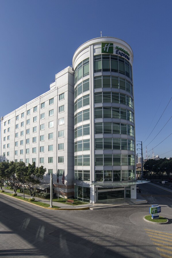 A modern hotel building with a curved glass facade, multiple floors, and a prominent entrance.