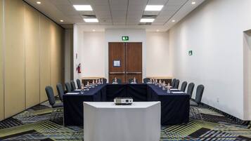 A conference room with a long table, chairs, a projector, and water bottles.