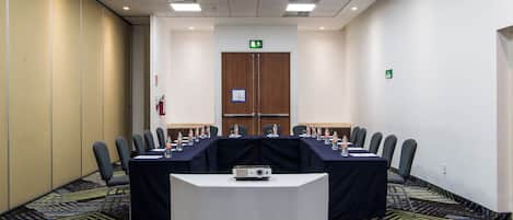 A conference room with a long table, chairs, a projector, and water bottles.