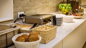 A buffet setup with bread, pastries, and a fruit bowl. - Facon del Mar Hotel (Mar Del Plata)