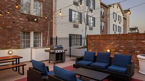 An outdoor patio with wicker furniture, a grill, and string lights. - TownePlace Suites by Marriott Sunnyvale Silicon Valley (Sunnyvale)