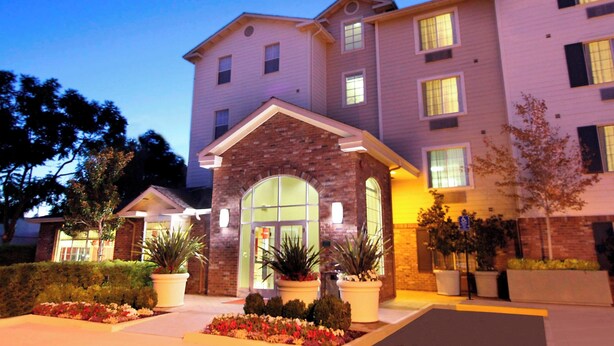 A multi-story hotel with a stone facade entrance, large windows, and potted plants in the landscaping. - TownePlace Suites by Marriott Sunnyvale Silicon Valley (Sunnyvale)