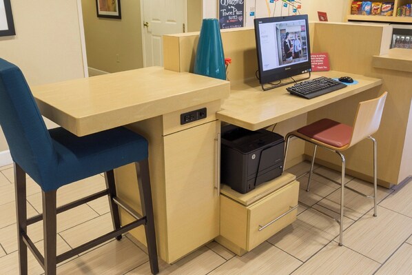 A workspace with a desk, chair, computer, printer, and storage drawer.