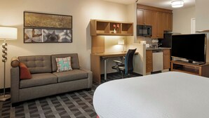 A hotel room with a bed, a sofa, a desk with a chair, a television, a microwave, and a small kitchenette. - TownePlace Suites by Marriott Sunnyvale Silicon Valley (Sunnyvale)