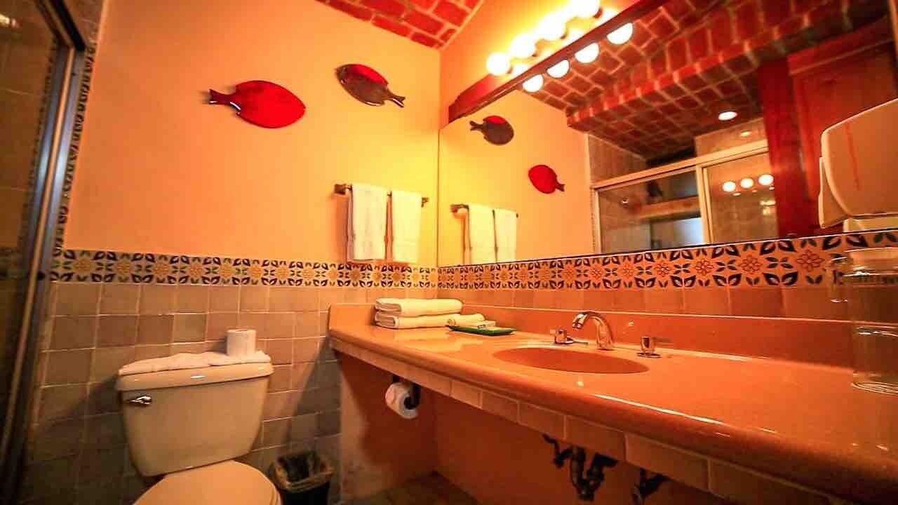 A bathroom with a toilet, sink, and mirror.