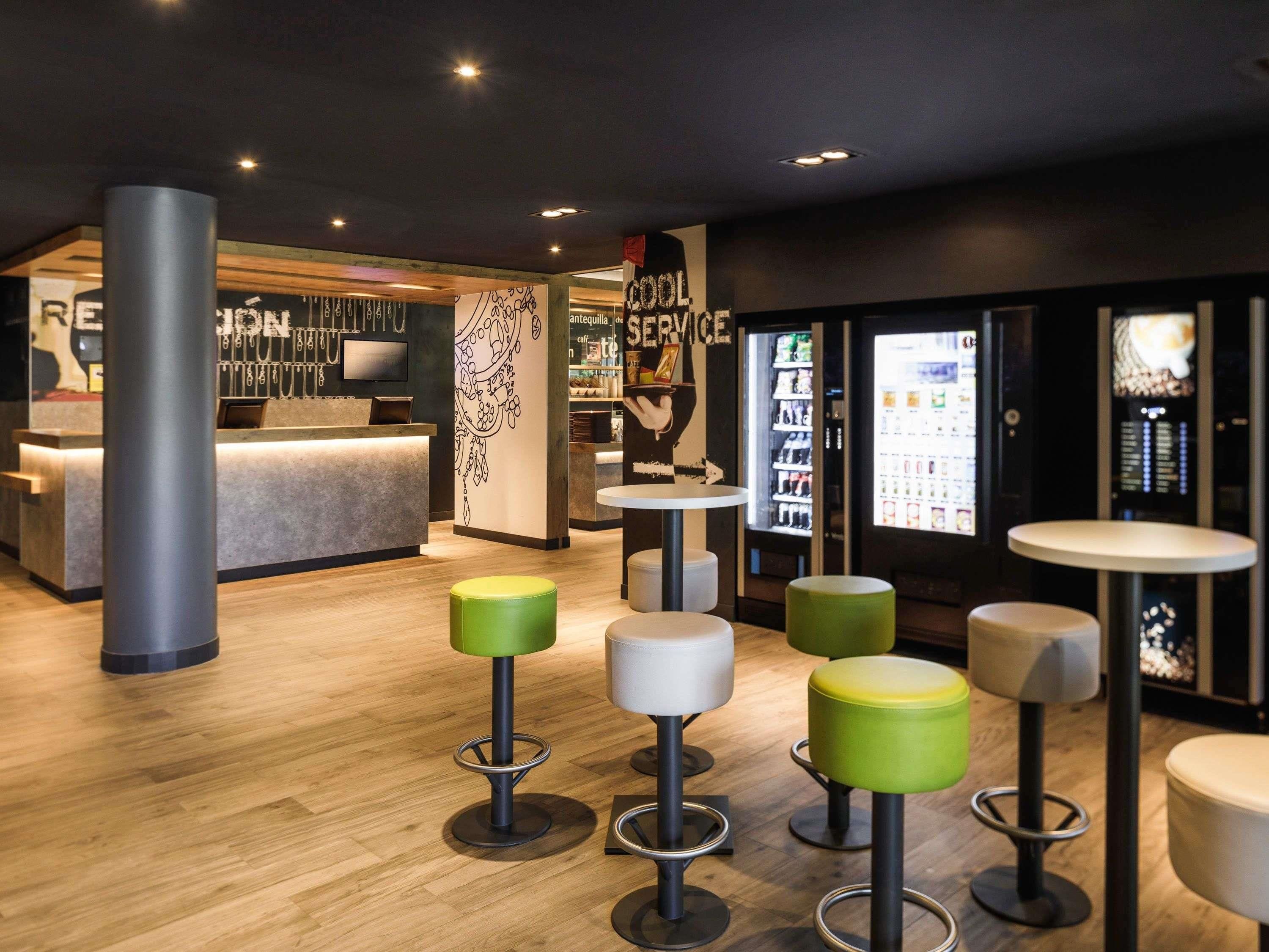 A modern bar area with stools, a counter, and a refrigerator.