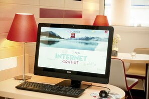 A computer monitor displaying a hotel website with "Free Internet" text, a keyboard, a mouse, and a red lamp on a desk.