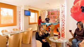 Relax in a stylish lounge area with comfortable seating, a large window, and a mounted TV.