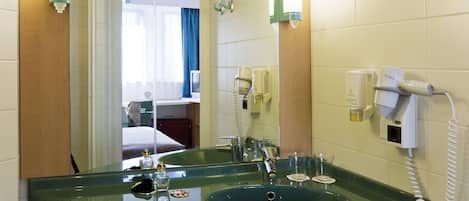Un baño con un lavamanos verde, un espejo, un secador de pelo y un perchero para toallas.