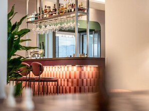 A bar area with a counter, shelves with bottles, and hanging glasses. - TRIBE Düsseldorf (Düsseldorf)