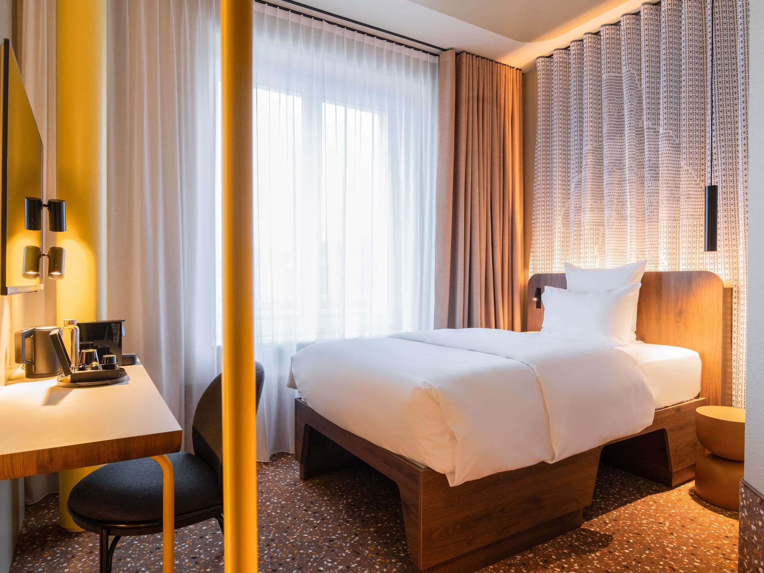 A hotel room with a bed, a desk, a chair, and a small table with a coffee maker.