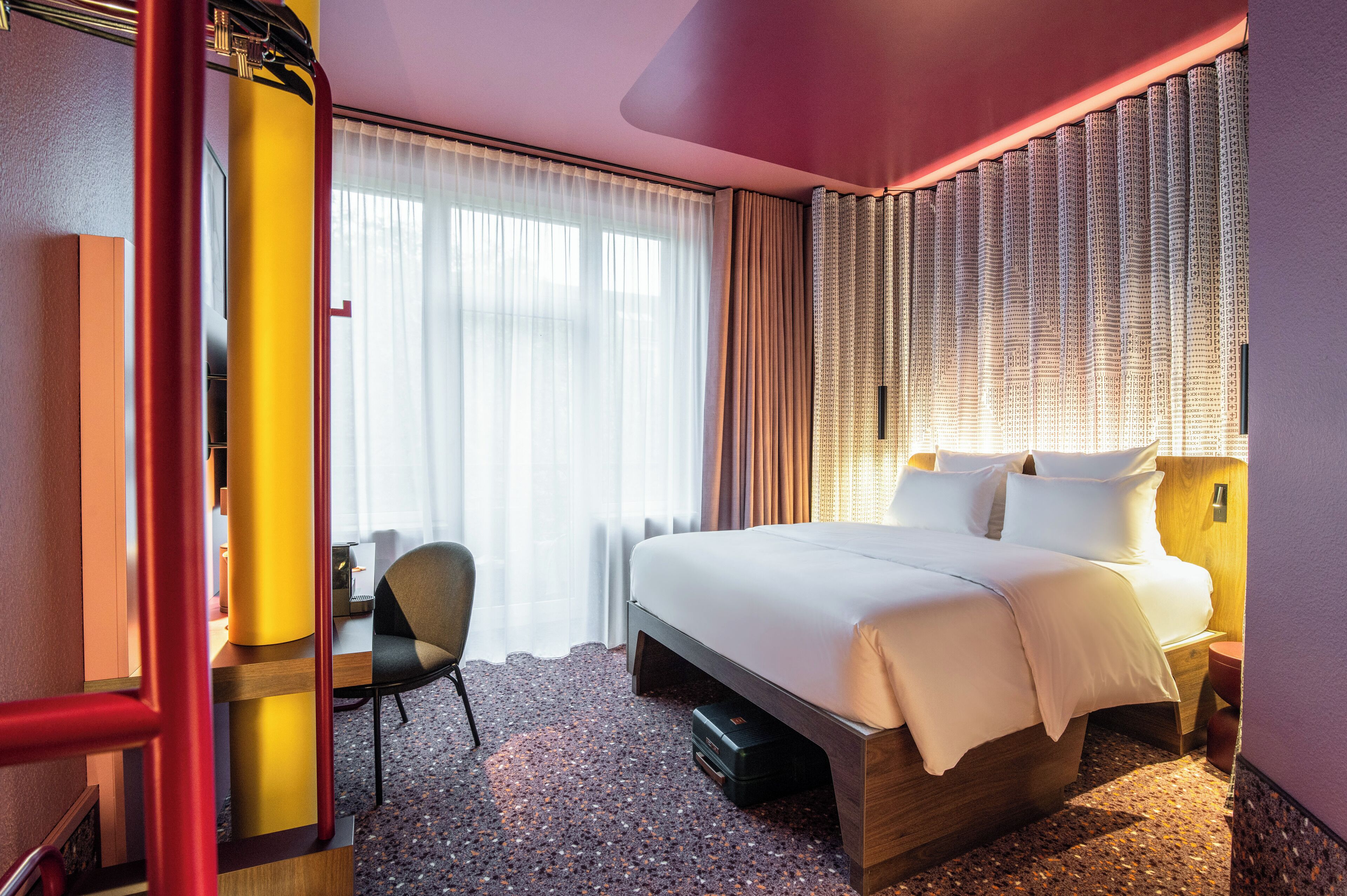 Une chambre d’hôtel avec un lit, un bureau et une chaise.