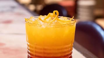 A glass with a layered drink, ice cubes, and a lemon garnish.