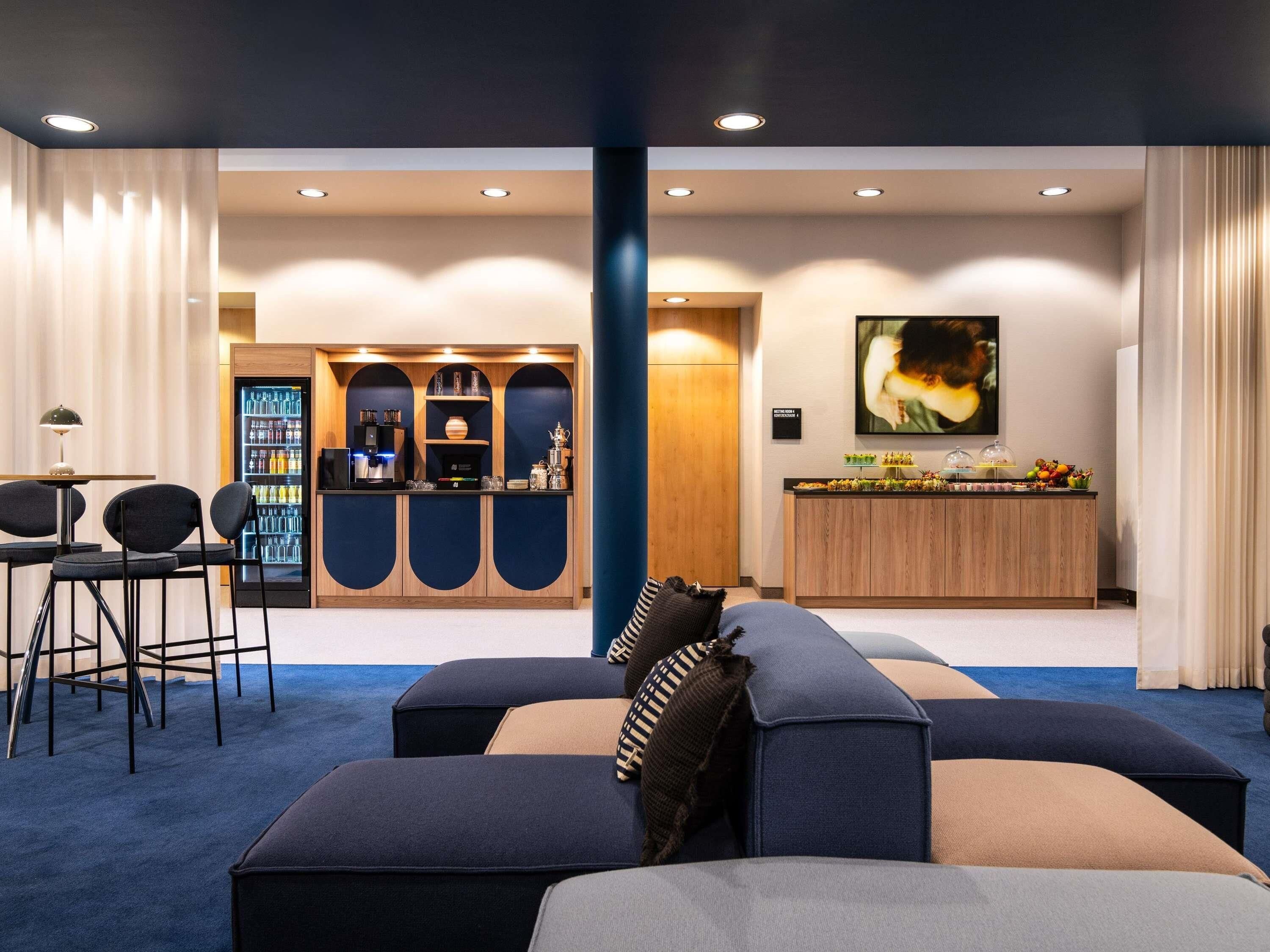 Un hall d’hôtel moderne doté d’un espace salon, d’un bar et d’une grande œuvre d’art accrochée au mur.