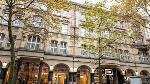 Un edificio storico con finestre ad arco e un negozio con scritto "TRIBE".