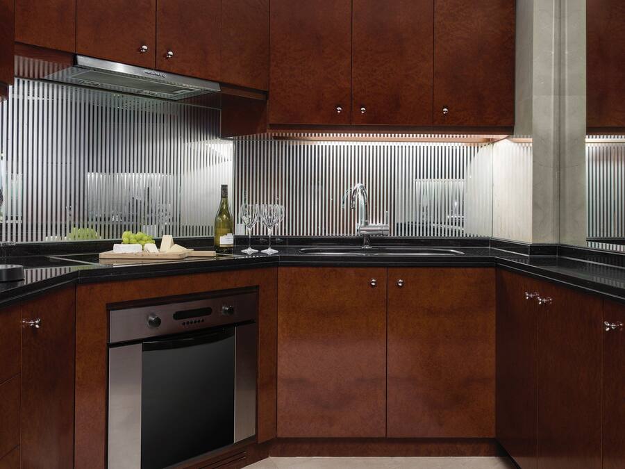 A modern kitchen with wooden cabinets, a stainless steel dishwasher, and a black countertop.