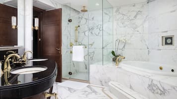 A modern bathroom with a double sink, a bathtub, and a glass-enclosed shower.