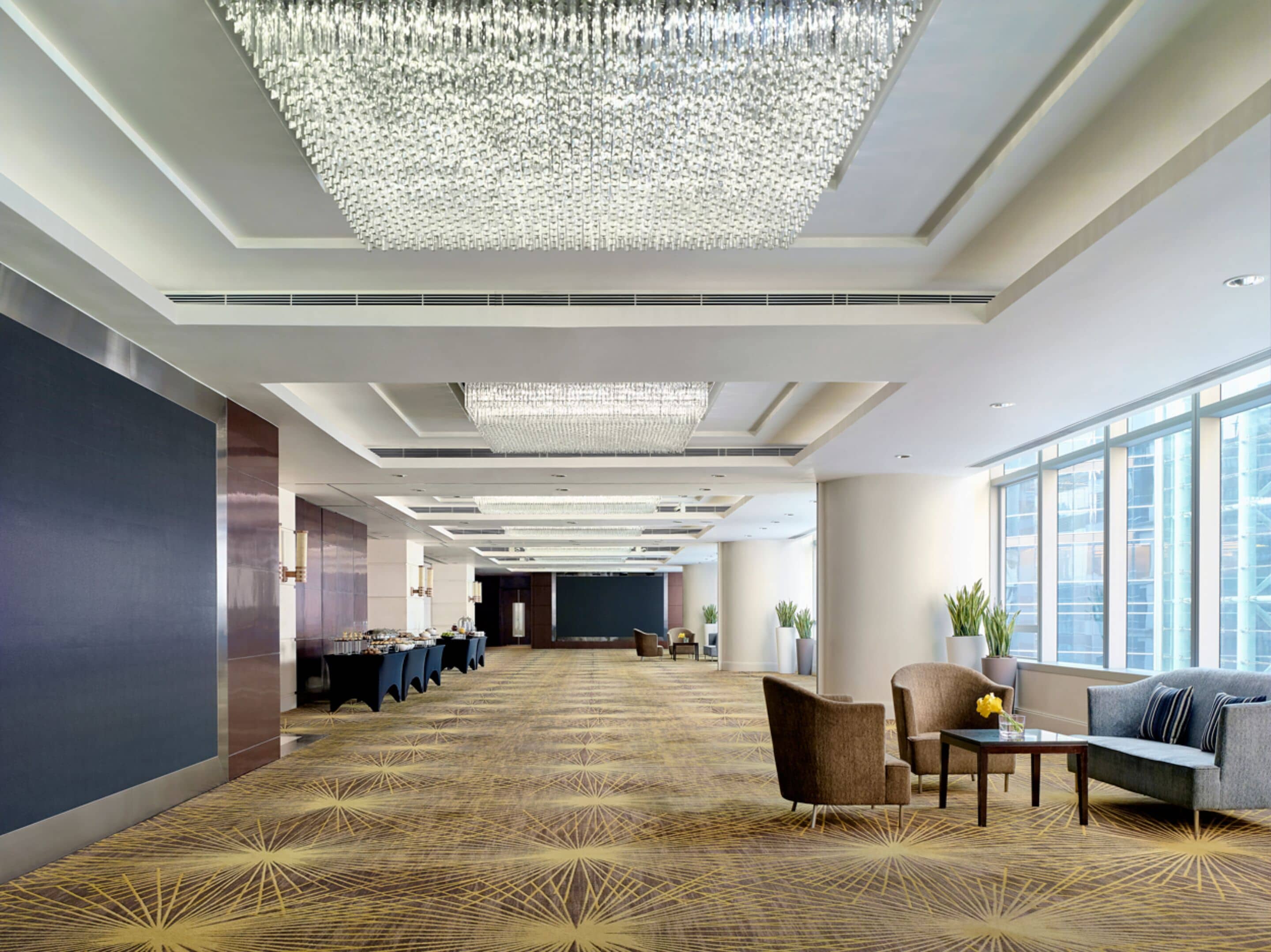 Un'ampia hall d'albergo con soffitto alto, un grande lampadario e una moquette decorata.