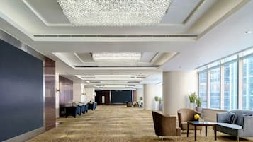 Un'ampia hall d'albergo con soffitto alto, un grande lampadario e una moquette decorata.
